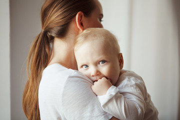 Mother holds baby with serous face in her arms