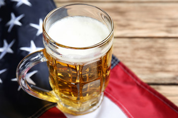 Glass of beer and American flag on table