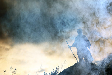 Wall Mural - Silhouette of a warrior with a sword in the smoke of a mountain war