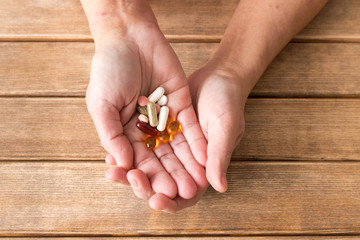 Wall Mural - Hands of the girl with atopic dermatitis with tablets . On the background of wooden table