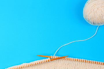 Wall Mural - Knitting with wooden knitting needles and wool yarn ball on blue background