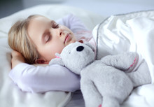 Child Little Girl Sleeps In The Bed With A Toy Teddy Bear