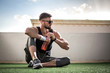 Young man in sports clothing with sunglasses take a break after training at rooftop gym.