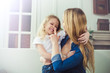 © My Ocean studio - Smiling and happy mom and daughter are hugging each other at home on the couch. Mom and daughter  have fun.