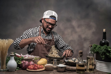 Wall Mural - Handsome bearded cheef cook prepairing spaghetti