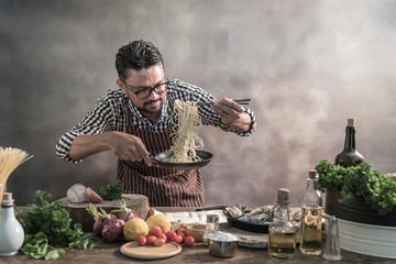 Wall Mural - Handsome bearded cheef cook prepairing spaghetti on a kitchen.