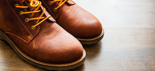 brown leather boots shoes on the brown wooden table background.with copy space.