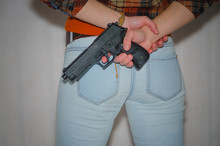 Girl Behind Holding A Pistol, On A Gray Background