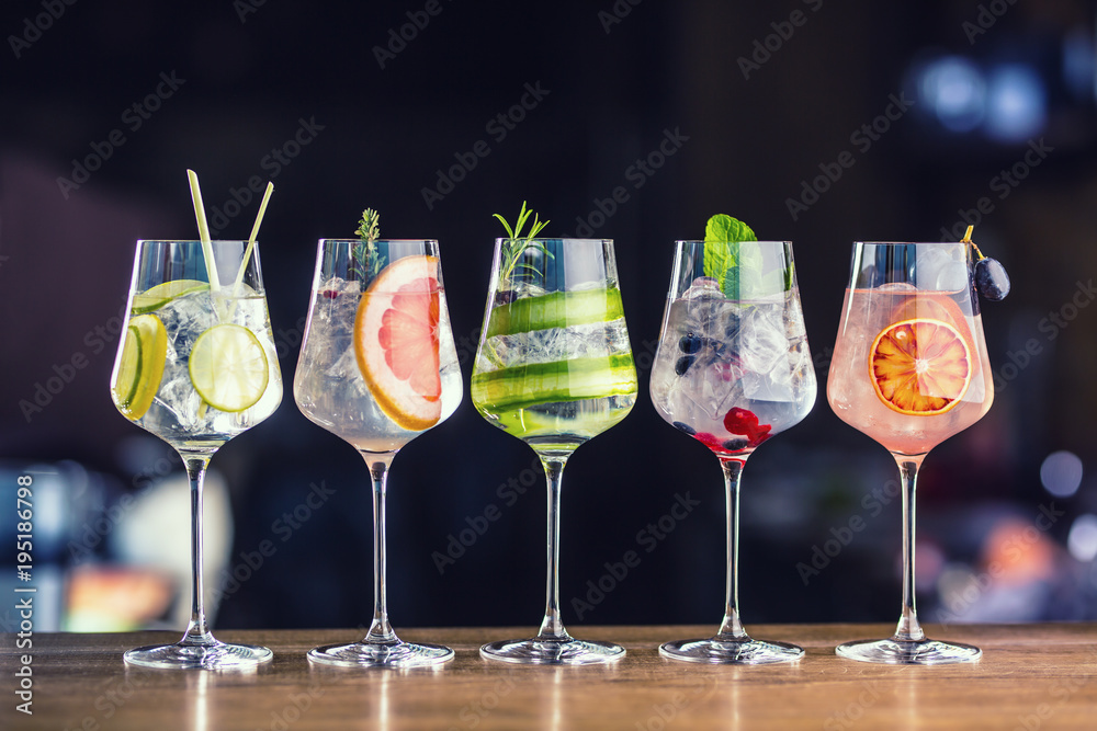 Five colorful gin tonic cocktails in wine glasses on bar counter in pup or restaurant - obrazy, fototapety, plakaty 