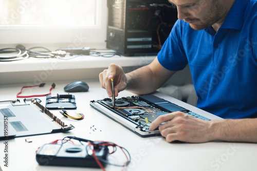 Fotomural computer repair service - technician repairing broken laptop in office