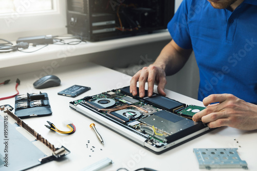 Fotografía computer repairman installing new hard disk drive in laptop