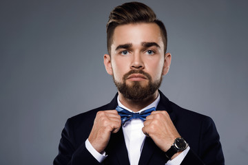 Wall Mural - Stylish handsome man wearing a classic suit with bow-tie