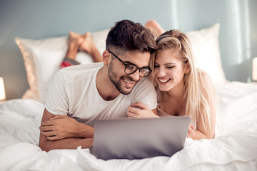 Wall Mural - Young couple with laptop in the bed.