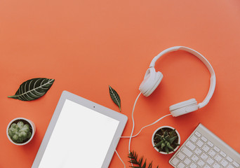 Creative flat lay of workspace desk, office stationery, keyboard, headphones and lifestyle objects on orange background with copy space