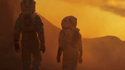Wall Mural - back view of the two astronauts wearing space suits walk exploring mars/ red planet. space travel, e