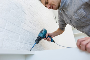 Man assembling kitchen cupboard using screwdriver