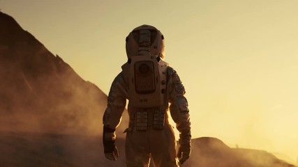 following shot of astronaut confidently walking on mars. red planet covered in gas and smoke. humans