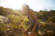 © Joshua Resnick - fit female hiker holding water bottle walking through nature at sunset