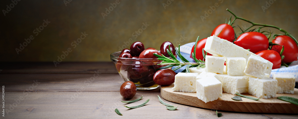 Feta cheese with kalamata olives, tomatoes and rosemary on a wooden background with space for text - obrazy, fototapety, plakaty 