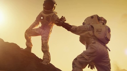 Wall Mural - two astronauts climbing mountain hill helping each other, reaching the top. overcoming difficulties.