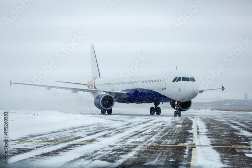 Airliner on runway in blizzard. Aircraft during taxiing at heavy snow