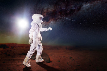 Wall Mural - Portrait of astronaut in a space suit. Futuristic astronaut on the planet, standing and stretches hand away
