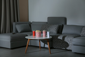 Canvas Print - Popcorn and drink on side table near comfortable sofa in home cinema. Watching movie