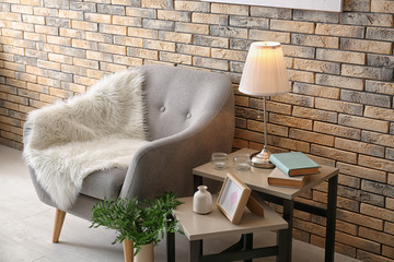 Wall Mural - Elegant table lamp and comfortable armchair in room interior near brick wall