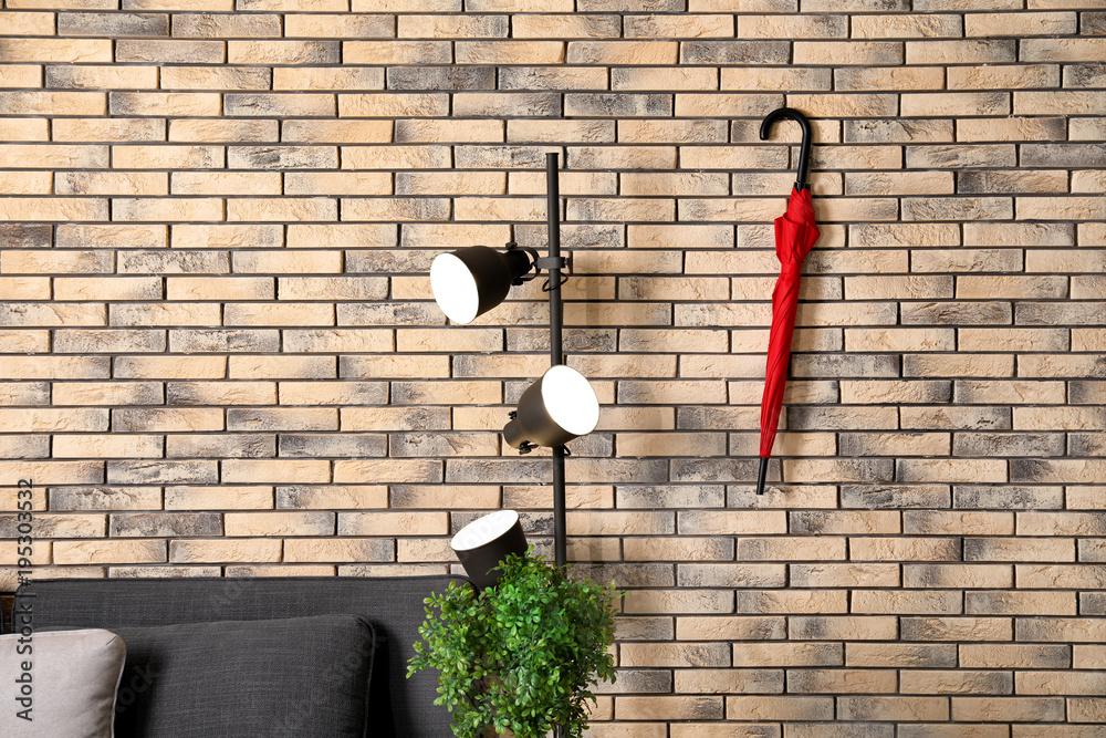 Stylish red umbrella hanging on brick wall