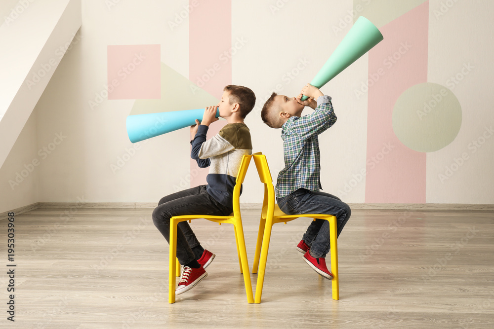 Funny little boys with paper megaphones indoors