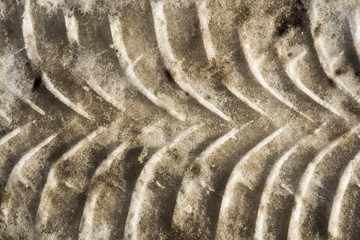 Diagonal traces of car tires on a dirty snow