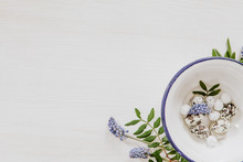 Natural Easter Decoration With Eggs In A Bowl And Grape Hyacinths In The Corner Of White Wooden Background