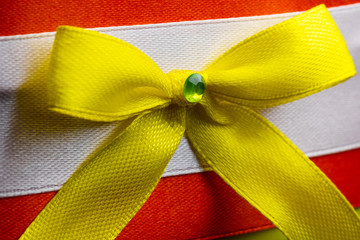 bow of yellow ribbon on the background of red and white fabric home handicrafts