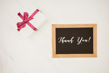 Wall Mural - top view of blackboard in frame with THANK YOU lettering and gift box isolated on white