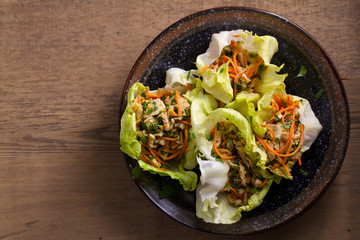 Lettuce wraps with chicken, carrot, peanuts and scallion. Stuffed iceberg lettuce leaves with chicken. View from above, top