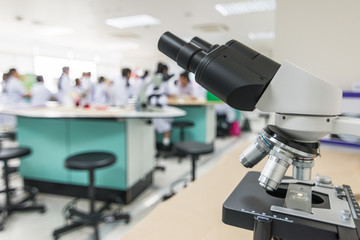 Biology or chemistry science class study with microscope and blur background of school student group learning in blurry lab classroom with teacher for education concept