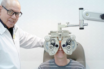 Man ophthalmologist examining patient man with optometrist trial frame. Male patient to check vision in ophthalmological clinic