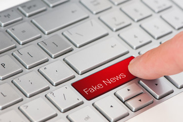 A finger press red fake news button on laptop keyboard