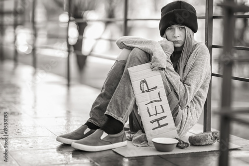 Fotografía Homeless poor teenage girl holding piece of cardboard with word HELP outdoors