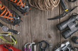 © martingaal - Top view of rock climbing equipment on wooden background. Chalk bag, rope, climbing shoes, belay/rappel device, carabiner and ascender. Active lifestyle concept.