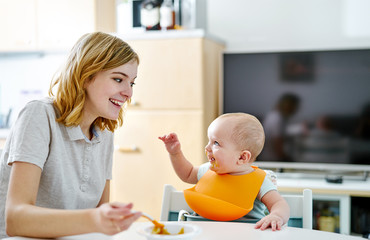 Happy mother and baby boy smiling during eating