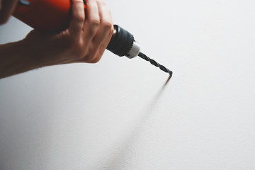 Sticker - Drilling in the wall. The man is holding a screwdriver or drill in hand. Drills a hole in the wall using a drill with a drill. Concept of housework, renovation at home, apartment.