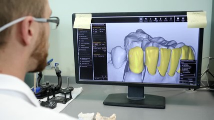 modern technologies in dentistry, young engineer in 3D glasses looks on model of human teeth on computer at laboratory