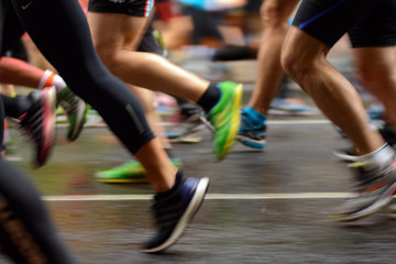 male and female runner's legs on asphalt. marathon