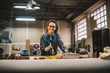 © Dusan Petkovic - Portrait view of happy attractive hardworking middle aged professional female worker painting wood with black color in the sunny workshop or garage.