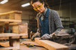 © dusanpetkovic1 - Portrait view of happy attractive hardworking middle aged professional female carpenter worker looking and choosing wood in the workshop or garage.