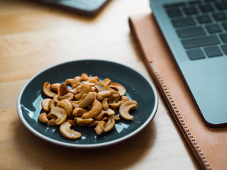 Some cashew nuts on small snack dish on work desk.