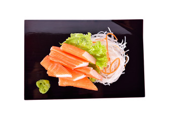 top view crab sticks with wasabi on black plate and on white background