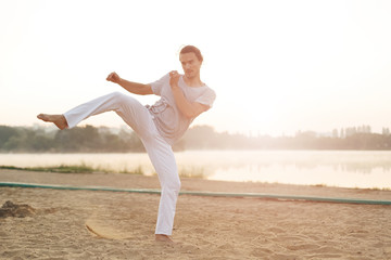 Wall Mural - Athletic capoeira performer workout training on the beach sunris