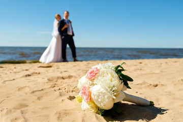 Wedding bouquet of flowers on wedding couple background, hugging at the beach. Panorama